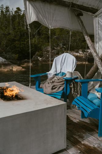 a tent with a table and a chair and a fire at Lux Remote Glamping Hideaway in Ucluelet