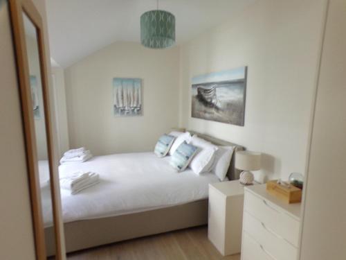 a bedroom with a bed with white sheets and blue pillows at 3TheDome - Luxury Ground Floor Apartment opposite the Beach, Barton on Sea in Barton on Sea