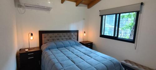 a bedroom with a blue bed and a window at Alto del pinar in Mar Azul