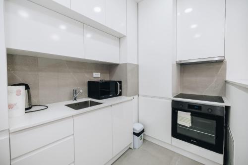 a white kitchen with a sink and a microwave at LUST PREMIUM Apartments in Kragujevac