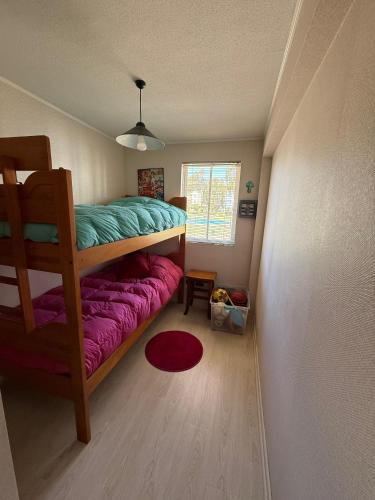 a bedroom with a bunk bed with a purple blanket at Departamento en Algarrobo Condominio Altos de Mirasol in Algarrobo