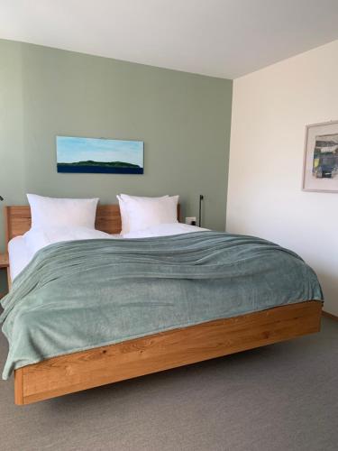 a bedroom with a large bed with a green blanket at Hotel Restaurant Croix Blanche in Sugiez