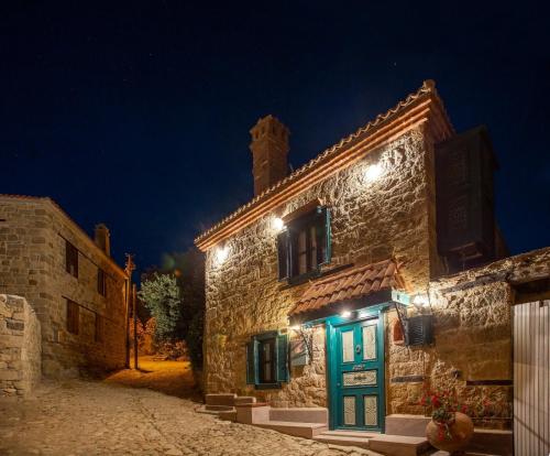 a stone building with a green door at night at Orion Adatepe in Adatepe