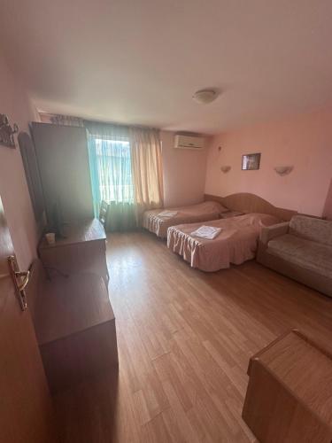 a hotel room with two beds and a couch at Hotel MERIDA in Blagoevgrad
