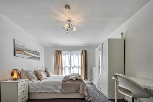 a white bedroom with a bed and a chandelier at Central Nottingham 3 bed house with Driveway in Nottingham