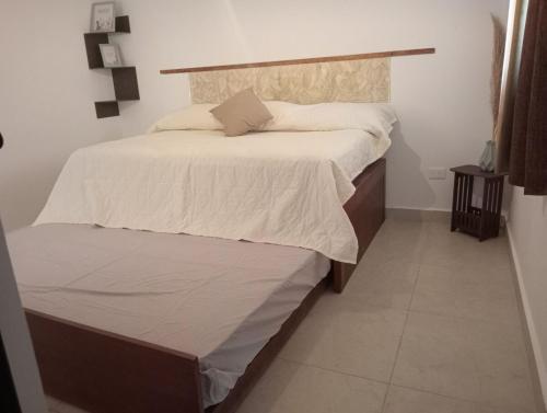 Un dormitorio con una cama grande con sábanas blancas. en Departamento Relax, en Mazatlán