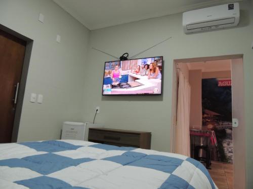 a bedroom with a flat screen tv on the wall at Pousada Cusco - Centro de Jaraguá do Sul in Jaraguá do Sul