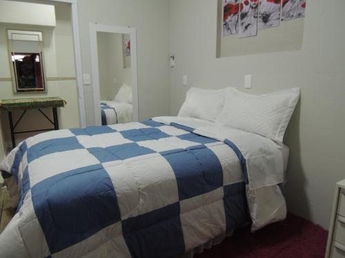 a bedroom with a bed with a blue and white blanket at Pousada Cusco - Centro de Jaraguá do Sul in Jaraguá do Sul