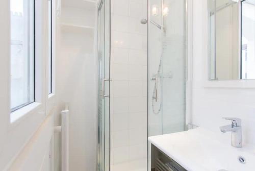 une salle de bain blanche avec une douche et un lavabo dans l'établissement Lovely apartment 10 min walk to Louvre 3 Persons, à Paris