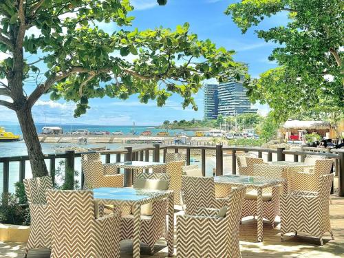 a patio with tables and chairs and a beach at The Mactan Newtown Beach Condo in Lapu Lapu City