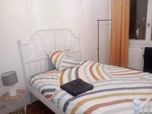 - un lit blanc avec une couverture rayée dans l'établissement Pleinitude 4 avec 2 chambres à louer separement, au Mans