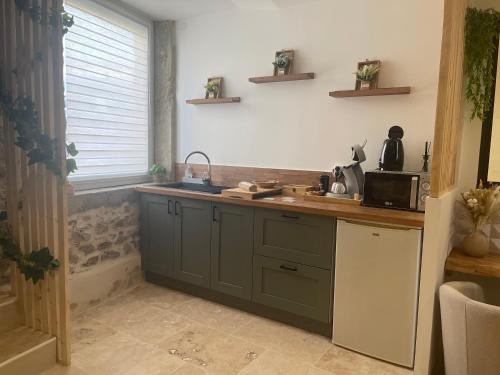 Il comprend une cuisine équipée d'un évier et d'un comptoir avec un four micro-ondes. dans l'établissement Love room chambre romantique avec Jacuzzi, à Grézieu-la-Varenne