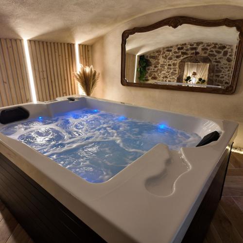 La salle de bains est pourvue d'une grande baignoire avec des lumières bleues. dans l'établissement Love room chambre romantique avec Jacuzzi, à Grézieu-la-Varenne