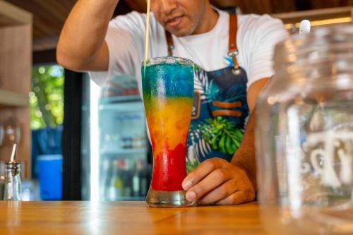 a man sitting at a table with a colorful drink at Pao Pao Hotel Islas del rosario in Isla Grande