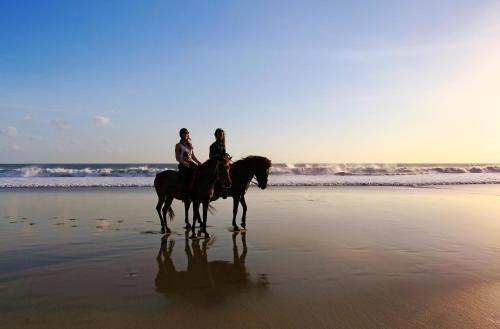 two people are riding horses on the beach at Pelangi Bali Hotel & Spa in Seminyak