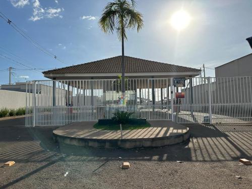 a white fence with a palm tree in front of a building at Concierge House Exclusiva in Marabá