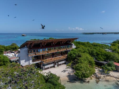 a building on the beach next to the water at Pao Pao Hotel Islas del rosario in Isla Grande