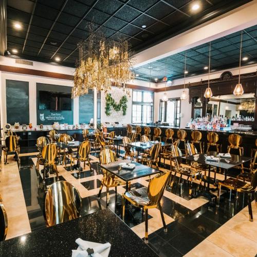 a restaurant with tables and chairs and a chandelier at Hotel Piccadilly in Fresno
