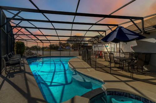 a swimming pool with an umbrella and chairs and a table at Debany Staycation near Disney in Kissimmee
