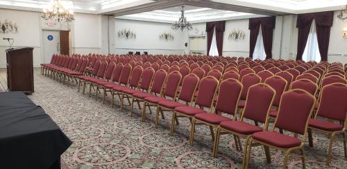 an empty room with red chairs and a podium at Hotel Piccadilly in Fresno