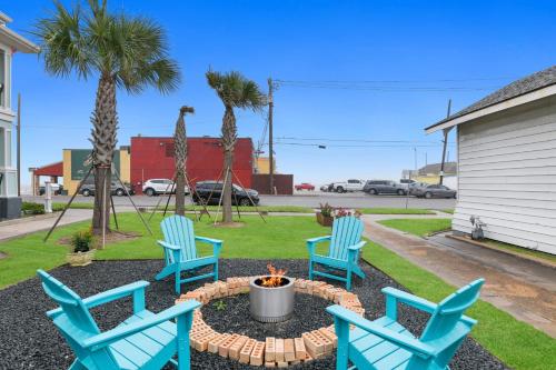 three blue chairs around a fire pit in a yard at The Grand on Ave O in Galveston