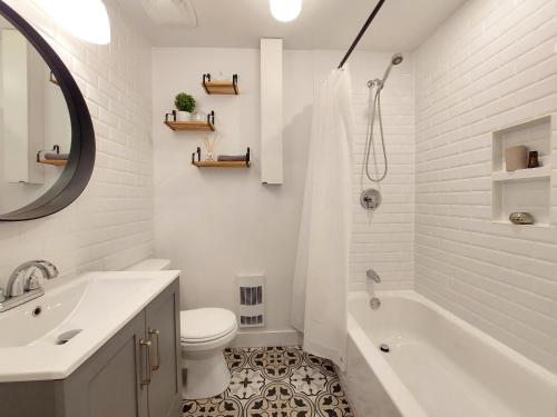 a white bathroom with a tub and a toilet and a sink at 25SV2-B1 Ouimetoscope in Quebec City