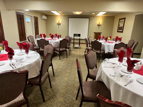 a room with tables and chairs with red roses on them at Hotel Piccadilly in Fresno