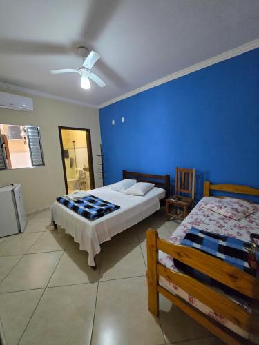 a bedroom with two beds and a blue wall at Suites Clima da Serra in Cunha