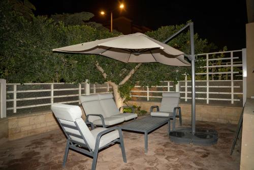 two chairs and an umbrella on a patio at night at Second Home Hospitality, Rehab City, New Cairo, Cairo Egypt in New cairo