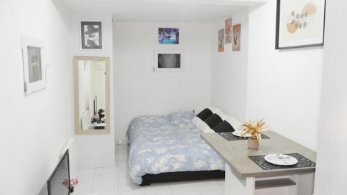 Un dormitorio blanco con una cama y una mesa. en Le Bac D'Eragny, en Éragny