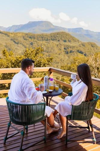 een man en vrouw aan een tafel op een dek bij Chalé Cordilheira Dos Canyons-2 in Praia Grande