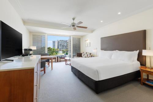 a hotel room with a large bed and a television at Pullman Reef Hotel Casino in Cairns