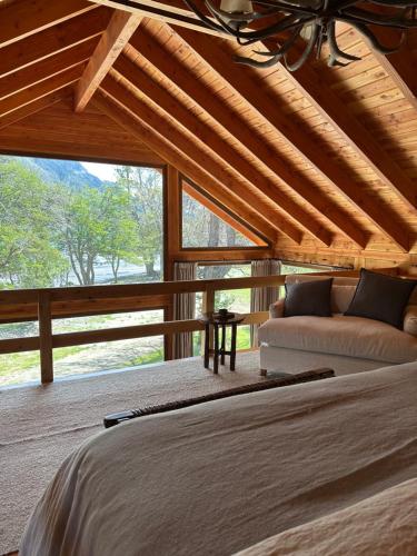 a bedroom with a bed and a couch and a window at El Pedregoso Cabaña del Lago in Cholila