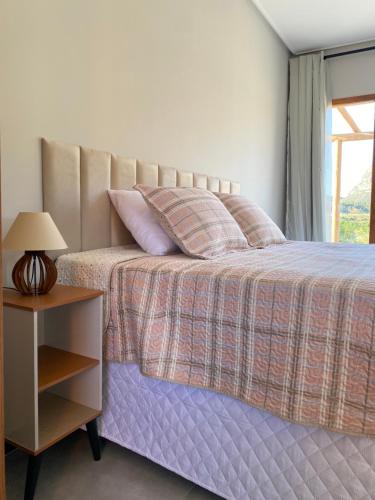 a bedroom with a bed and a table with a lamp at Chalé Frutas Especiais in Mucugê