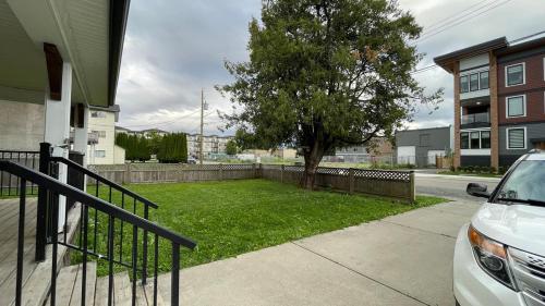 a car parked next to a yard with a tree at King and Queen rooms -J&J Chilliwack in Chilliwack