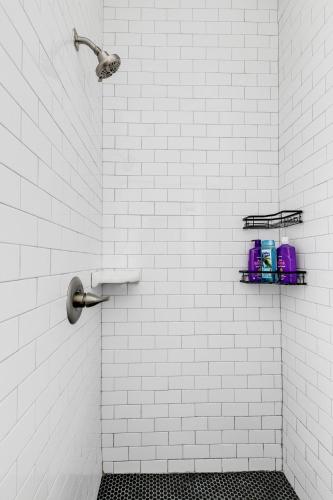 a white tiled bathroom with a shower with two shelves at Quaint Escape for 2 Near Richmond Battlefield Park in Richmond