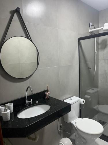 a bathroom with a sink and a toilet and a mirror at Casa na Praia da Pitoria in São Pedro da Aldeia
