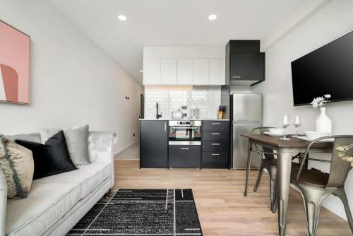 a living room with a couch and a table and a kitchen at Beautiful Designed Auckland CBD Studio Apartment - Pool Sauna Gym in Auckland