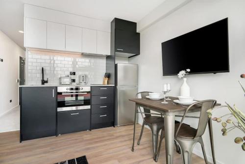 a kitchen with a table and a tv in it at Beautiful Designed Auckland CBD Studio Apartment - Pool Sauna Gym in Auckland