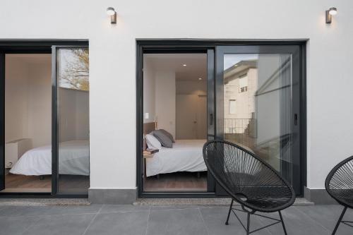 a room with glass doors and two chairs on a patio at Avós Apartamentos in Monforte de Lemos