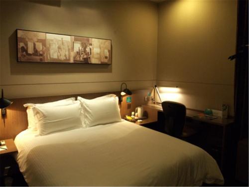 a hotel room with a bed and a desk and a bed sidx sidx at Jinjiang Inn Xiamen Jimei University Guomao in Xiamen