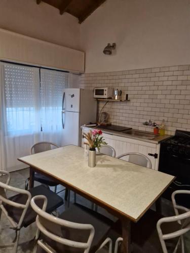 eine Küche mit einem Holztisch mit Stühlen und einem Kühlschrank in der Unterkunft Casa Chalet Lamar alojamiento entero in Santa Clara del Mar