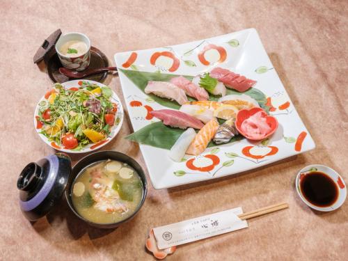 a table with two plates of food and a bowl of soup at 丘の上から海が見える一棟貸しヴィラ しまいろ長手 in Nagate