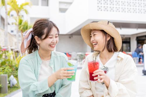 two girls are laughing and drinking a drink at Okinawa Hinode Resort and Hot Spring Hotel in Naha