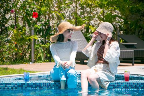 two women sitting in the water in a swimming pool at Okinawa Hinode Resort and Hot Spring Hotel in Naha