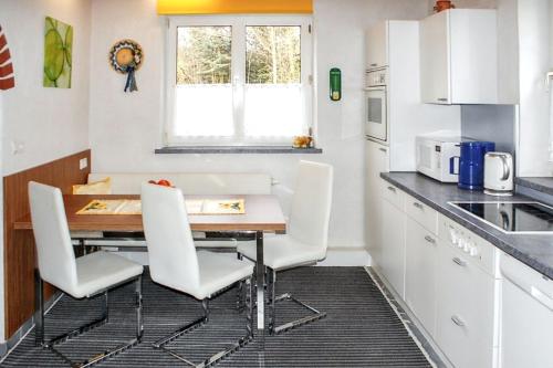 a kitchen with a wooden table and white chairs at Charming house in Purgstall with a private garden in Hart