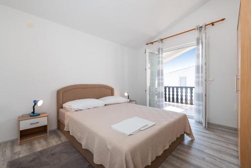 a white bedroom with a bed and a balcony at Apartments with a parking space Nin, Zadar - 23493 in Nin