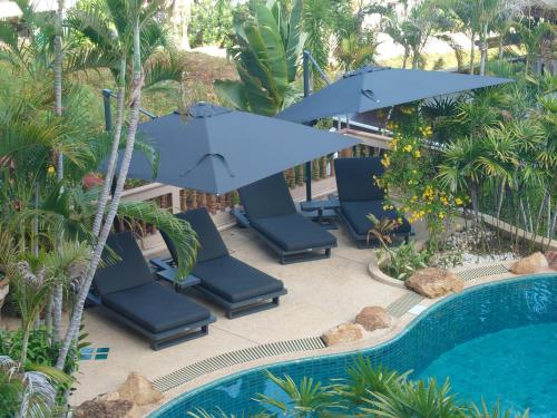 a pool with blue chairs and umbrellas next to a pool at Samui Little Garden Resort in Chaweng