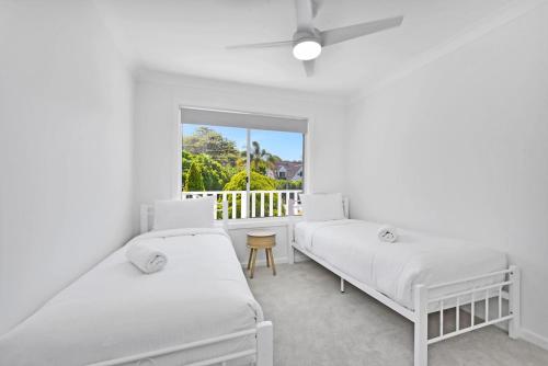 two beds in a room with a window at Gidget's Getaway in Nelson Bay