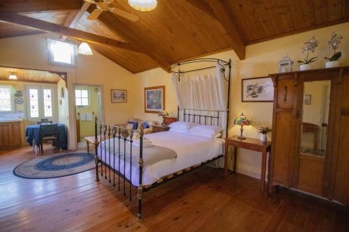 a bedroom with a bed in a room with wooden floors at Rose Petal Cottage Quaint Studio In Ballarat in Ballarat